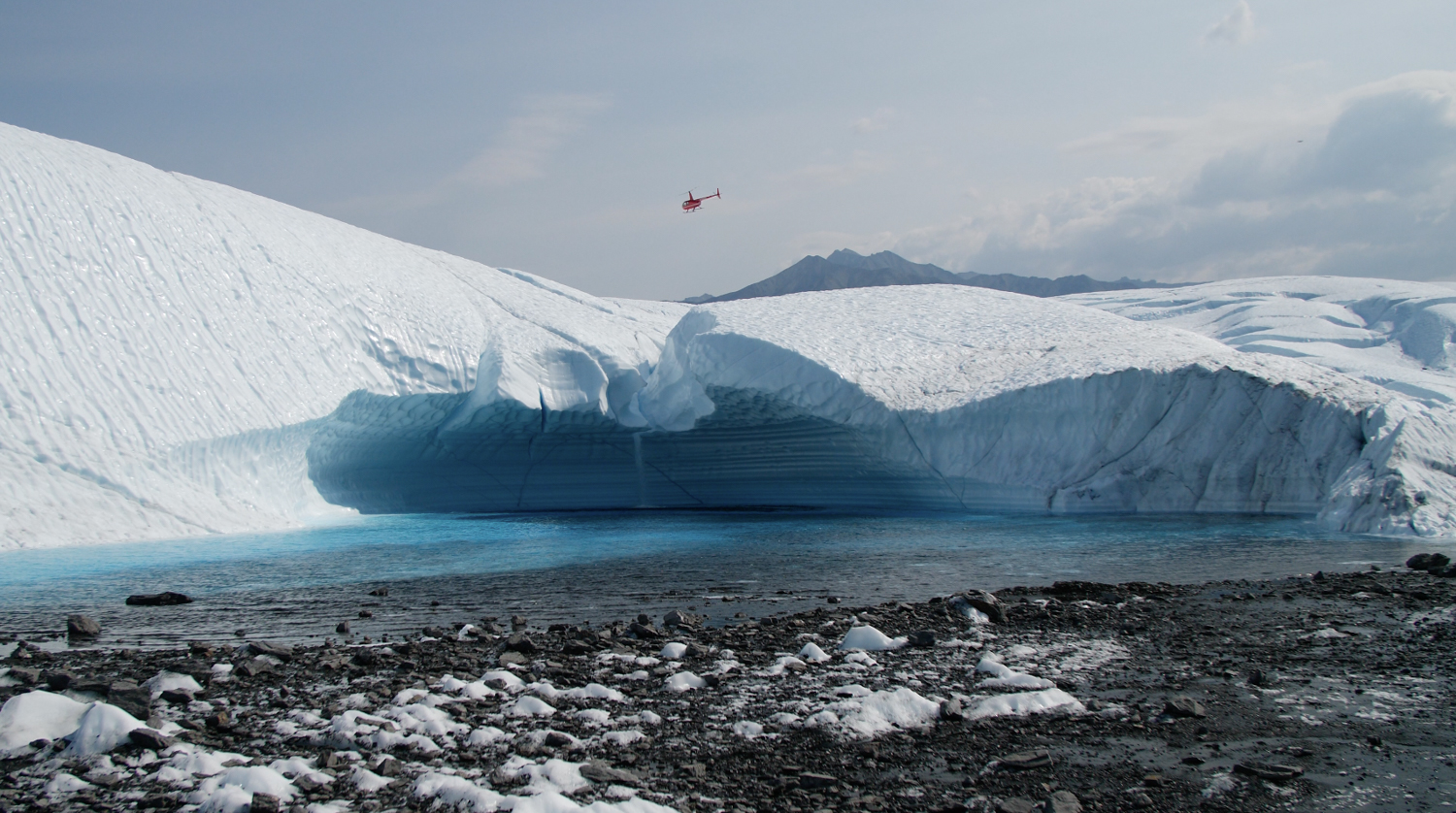 helicopter flying over blue ice waterfall