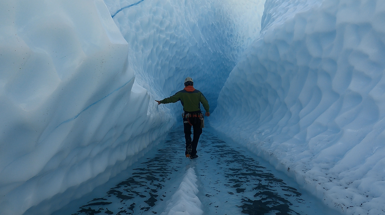 person walking down blue ice canyon